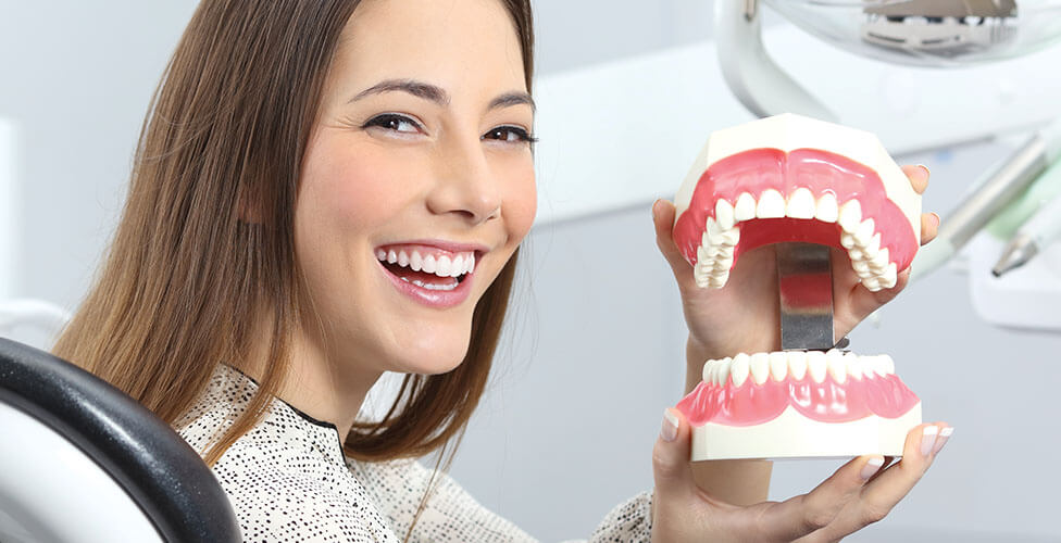 A patient in the dental chair at Al Care Dental, holding a model of a mouth